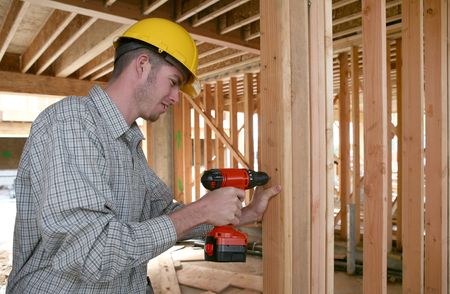 A handsome construction man using a drill to secure a beam