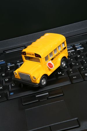 A yellow toy school bus on a laptop computer