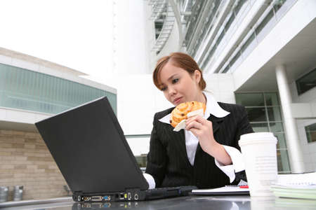 A pretty young woman eating and working on computerの写真素材