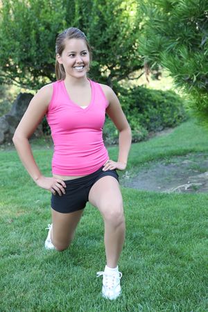 A pretty woman jogger stretching before running in the park