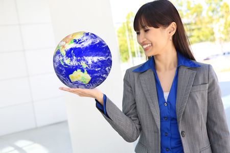 A pretty asian business woman at office holding globe of earthの写真素材