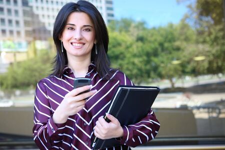 A young pretty business woman ouside office building textingの写真素材