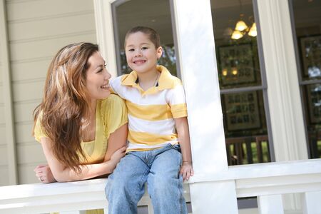 A cute boy and his mother on the porch at homeの写真素材