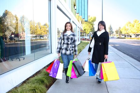 Pretty women shopping with colorful bags walking to the next storeの写真素材