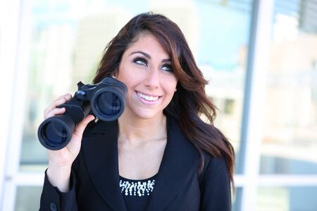 Young caucasian business woman with binoculars at office buildingの写真素材