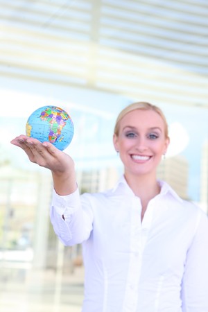 A beautiful young blonde woman holding a globe at office buildingの写真素材