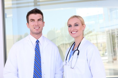 Handsome man doctor and woman nurse smiling in front of hospital の写真素材