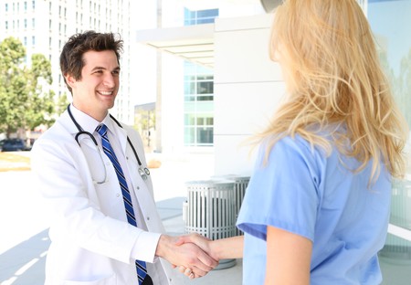 A man and woman medical team handshake outside hospitalの写真素材