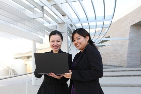 Two diverse business woman at office building with laptop computerの写真素材