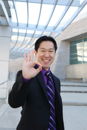 A handsome Chinese business man at office building indicating success  Focus on Hand の写真素材