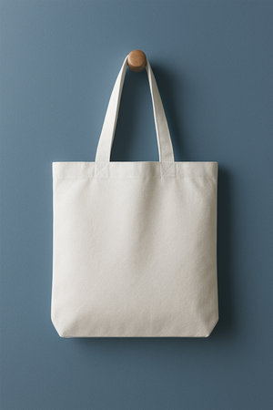 Hyper-realistic white tote bag mockup hanging on a blue wall hook, clean modern background, soft lighting, premium realistic fabric texture, product-focused designの素材