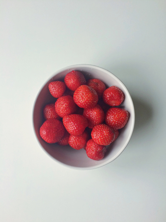 Red strawberries in a white bowl, center placed on white background,の写真素材