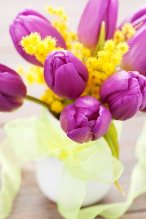 Purple tulips and mimosa in vaseの写真素材