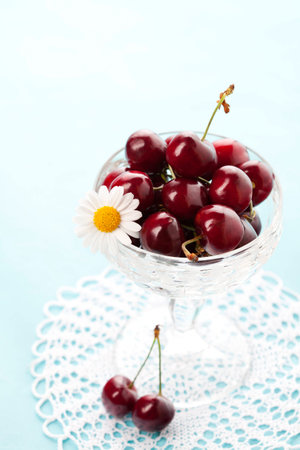 Fresh cherries in crystal vase  on blue の写真素材