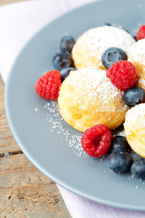 Traditional danish pancakes - ebelskivers with fresh berriesの写真素材