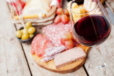Glass of red wine with charcuterie assortment on the backgroundの写真素材