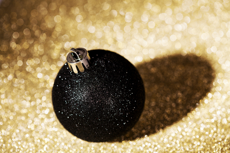 Black christmas ball on golden bokeh backgroundの写真素材