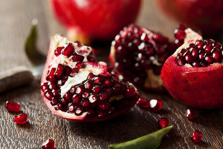 Open fresh ripe pomegranates on wooden backgroundの写真素材