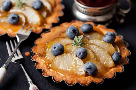 Homemade pear and blueberry tarts on blackの写真素材