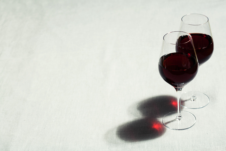 Two glasses of red wine on grey linen table cloth with copy spaceの写真素材