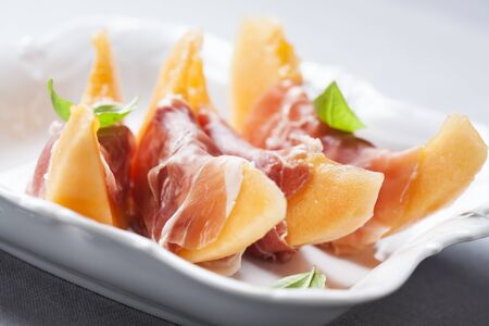 Slices of cantaloupe melon and prosciutto ham, shallow DOFの写真素材