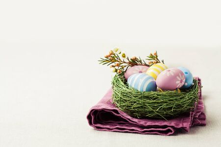 Colorful Easter eggs in nest on linnen cloth