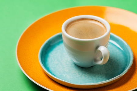 Cup of coffee on colorful tableware and bright backgroundの写真素材