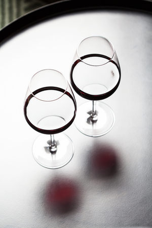 Silhouettes of two glasses of red wine on black tableの写真素材