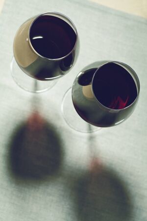 Two glasses of red wine with shadow on the tableの写真素材