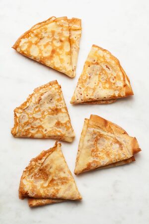 Several folded pancakes on white marble background