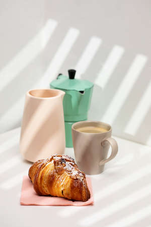Homemade almond croissant and coffee, morning light through the shuttersの写真素材