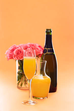 Mimosa cocktail in flute glass and roses in vaseの写真素材