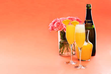 Mimosa cocktail in flute glass and roses in vase, copy spaceの写真素材