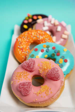 Assorted doughnuts on white plate, cyan backgroundの写真素材