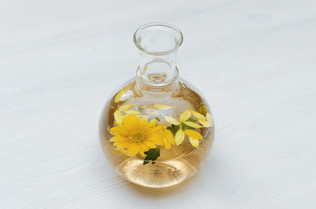 Chrysanthemum daisy flower essential oil tincture bottle on the white wooden table background with copy space. Herbal medicine.の写真素材