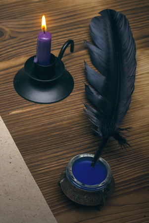 Candle, feather pen and inkstand on wooden table background.の写真素材
