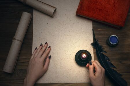 Female hand, blank paper page sheet with copy space and vintage books on wooden table background. Education concept. Back to school.の写真素材