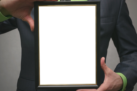 Diploma certificate of best worker or manager mock up. Businessman holding in hands a blank photo frame isolated on gray background. Close up photo.の写真素材