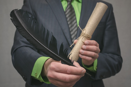 Businessman holds in hand a rolled up document scroll and feather pen. Signing of an agreement....
