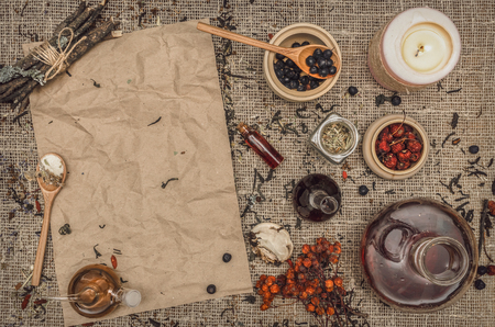 Herbal medicine concept background. Alternative medicine. Dry curative herbs and wild berry essential oil and blank crumpled paper page sheet (recipe, doctor prescription) on burlap sackcloth background with copy space.の写真素材