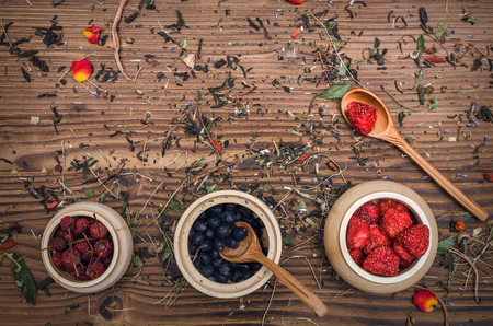 Alternative herbal medicine concept. Different wild berries and other organic ingredients on brown wooden table surface.の写真素材