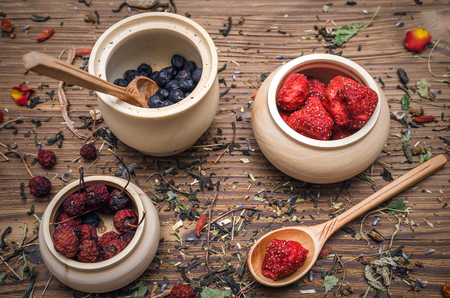 Alternative herbal medicine concept. Different wild berries and other organic ingredients on brown wooden table surface.の写真素材