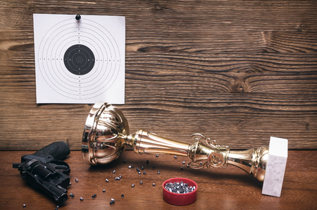 Best shooter award background with copy space. Winner in shooting. Gun, paper target and gold medal. Shooting range.の写真素材