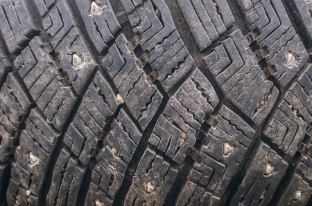 Old car tire tread texture background. Worn out protector of car tire. Used wheels close up.