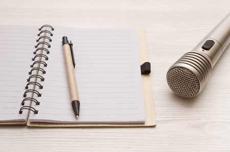 Audio recording studio desk table. Karaoke mock up. Microphone and blank page notepad with copy space for song lyrics on white table background.の写真素材