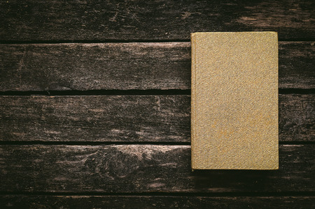 Closed golden book on the aged wooden table background. Writer table.の写真素材