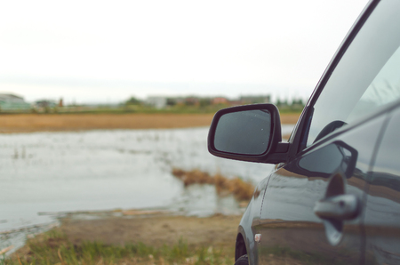 Gray car on the river lake shore in the rainy day. To drive away from the city.の写真素材