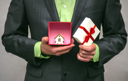 Real estate agent. Real estate agency. Insurance agent. Mortgage. Buy house. Present box with small toy house.の写真素材