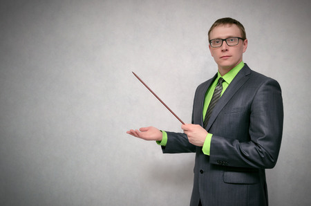 Business project or product presentation. Teacher or financial advisor or student with school pointer explains lesson theme isolated on gray background with copy space.の写真素材