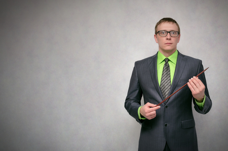 Business project or product presentation. Teacher or financial advisor or student with school pointer explains lesson theme isolated on gray background with copy space.の写真素材